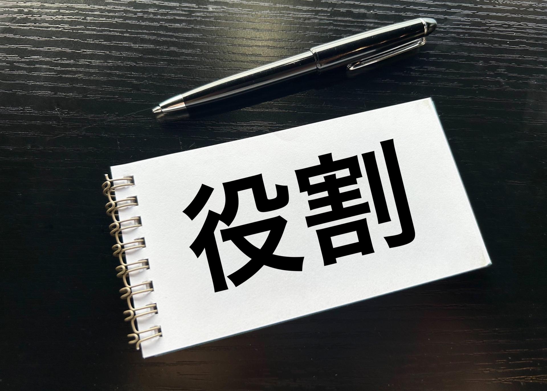 役割と書かれたメモ帳とペン