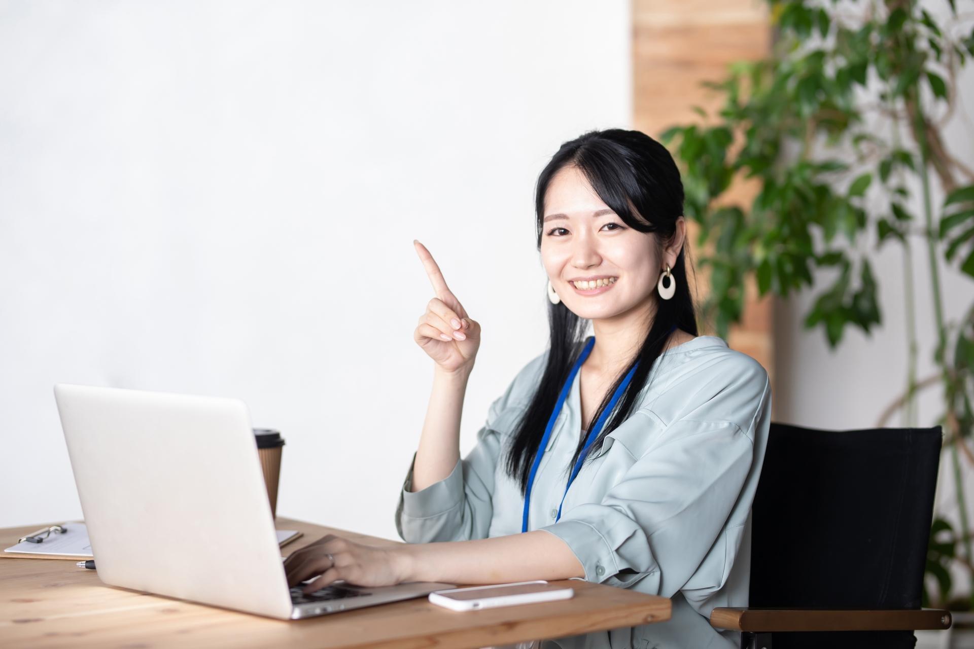 ノートPCを前に指を立てる女性